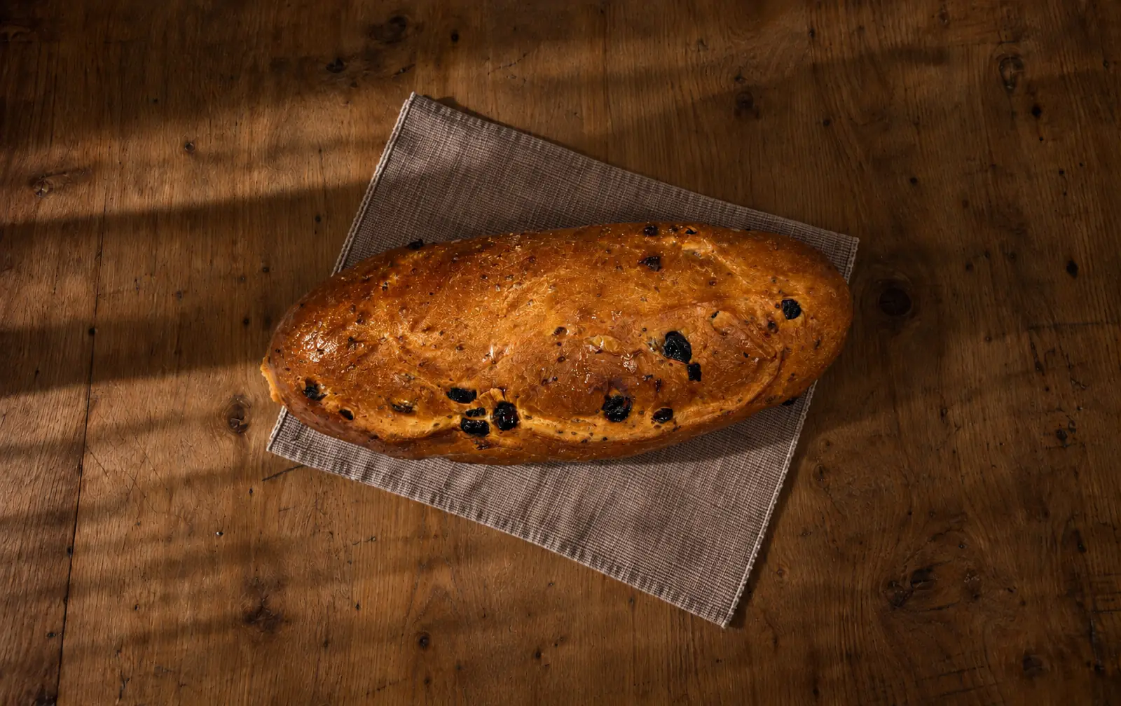 Il nostro buccellato lucchese con uvetta e semi di anice, dalla crosta lucida, su un tovagliolo su un tavolo di legno.